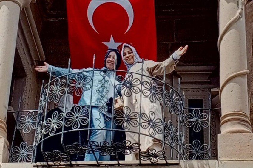 A balcony with ornate metal railings and a flag in the background. 4