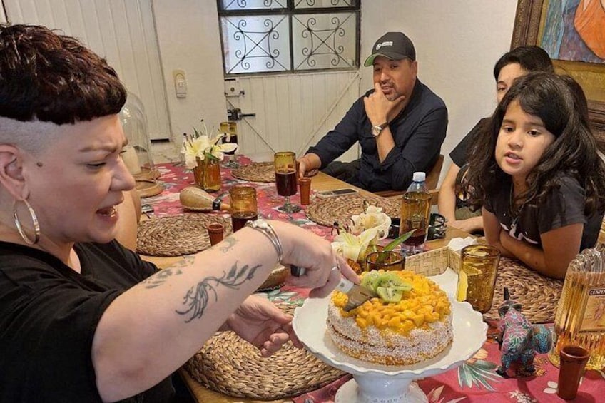 Un grupo de personas sentadas alrededor de una mesa con un pastel y bebidas. 2