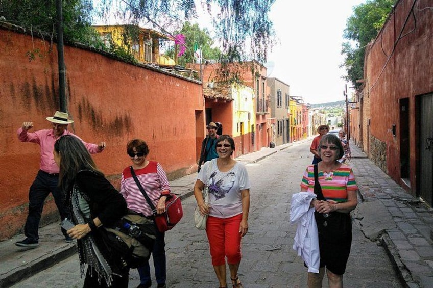 Un grupo de personas caminando por una calle estrecha con paredes y edificios a ambos lados. 3
