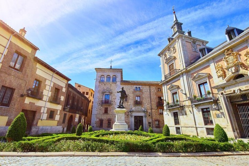 A historic square with a central statue, surrounded by classical architecture and well-maintained hedges. 4