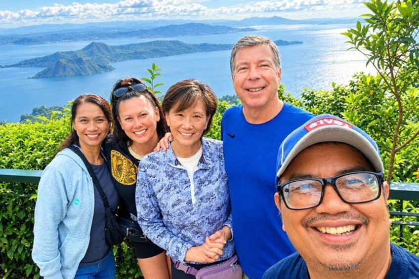 A group of people standing on a hill overlooking a body of water with mountains in the background. 4