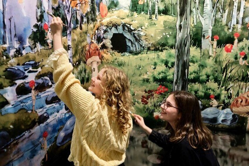 Two people interacting with a large, colorful mural. 3