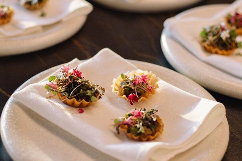 Una mesa con platos de comida, cada uno adornado con una tartaleta pequeña y flores decorativas. 4