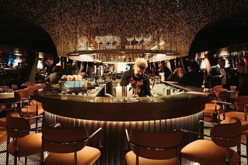 A bar with a bartender preparing drinks, surrounded by seated patrons. 4