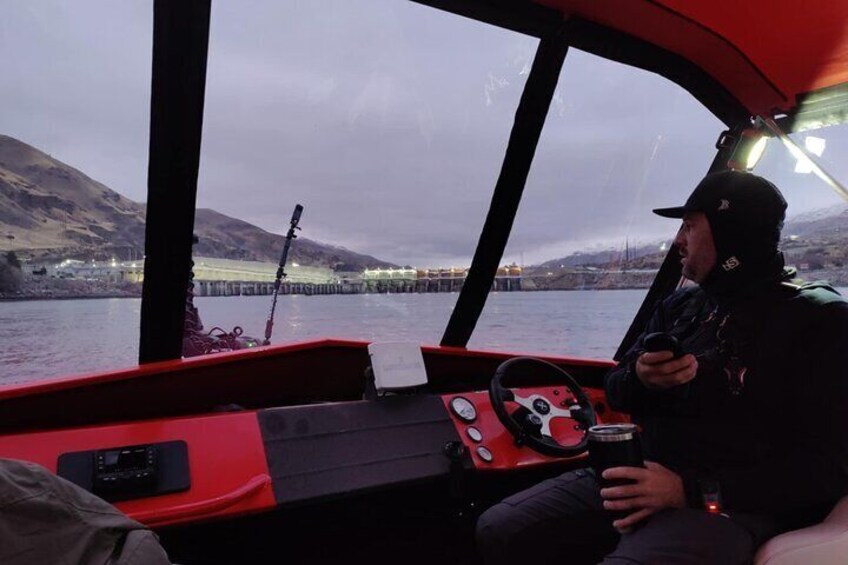 A person on a boat holding a camera, with a control panel and a red seat in the foreground. 5