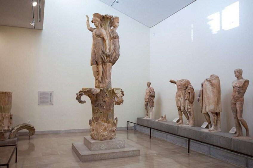 A museum interior with classical sculptures on pedestals. 2