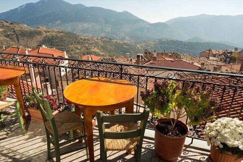 A terrace with a table and chairs, potted plants, and a view of a mountainous landscape. 5