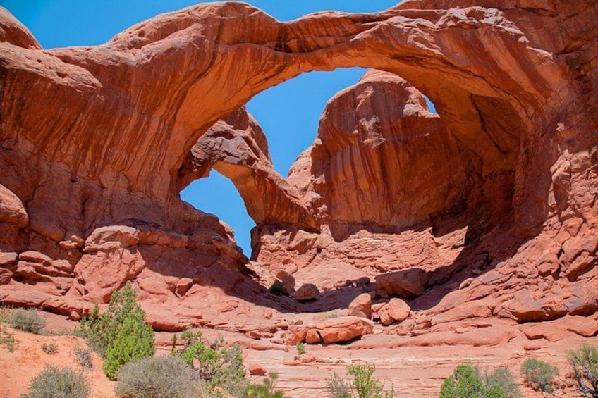 A large red rock arch formation with a clear blue sky above. 3