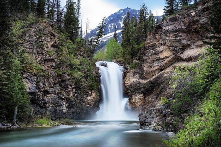 Una cascata circondata da scogliere rocciose e una fitta foresta. 5
