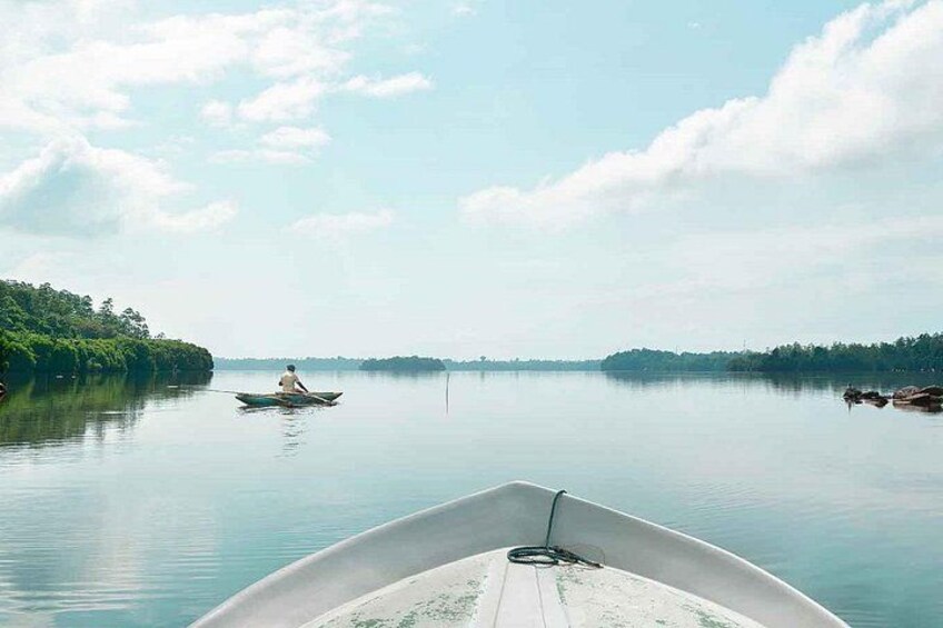 A calm lake with a boat in the foreground and another boat in the distance. 1