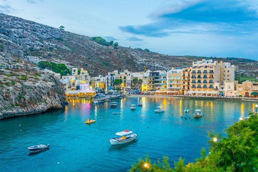 A coastal town with buildings, boats, and a rocky hillside. 2