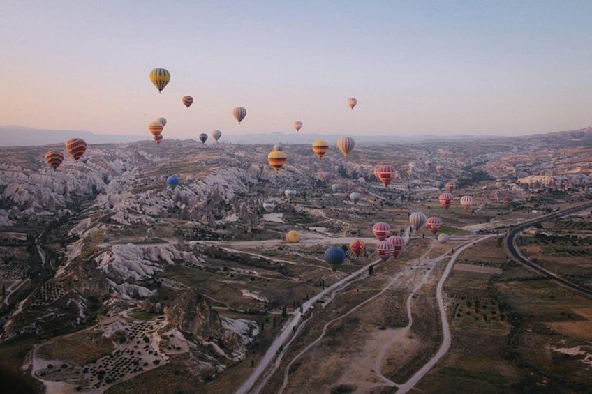 Eine Landschaft mit vielen Heißluftballons, Straßen und gebirgiger Landschaft. 2