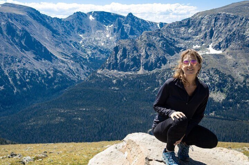 A person sitting on a rock with a mountainous landscape in the background. 2