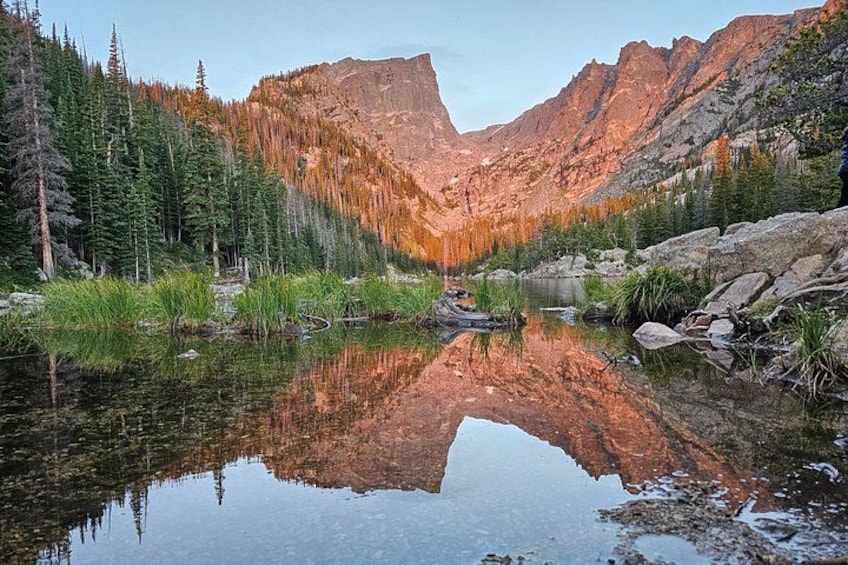 A mountain lake with reflections, surrounded by trees and rocky terrain. 1