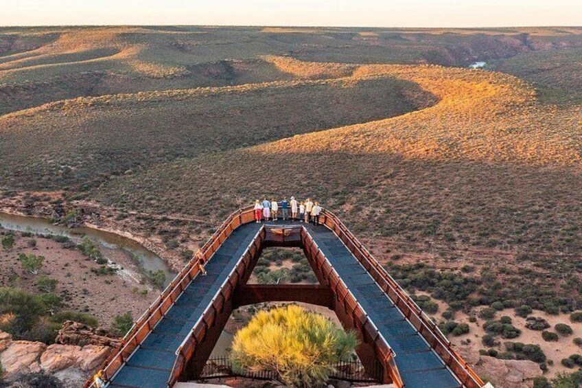 Een lange brug met voetgangers, omgeven door een woestijnlandschap met heuvels. 2