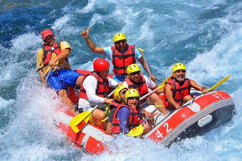 A group of people in a red and white inflatable raft navigating through rough waters. 1