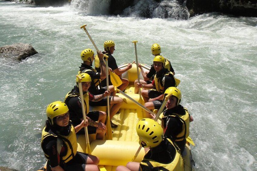 A group of people in a yellow raft navigating a river with rapids. 5