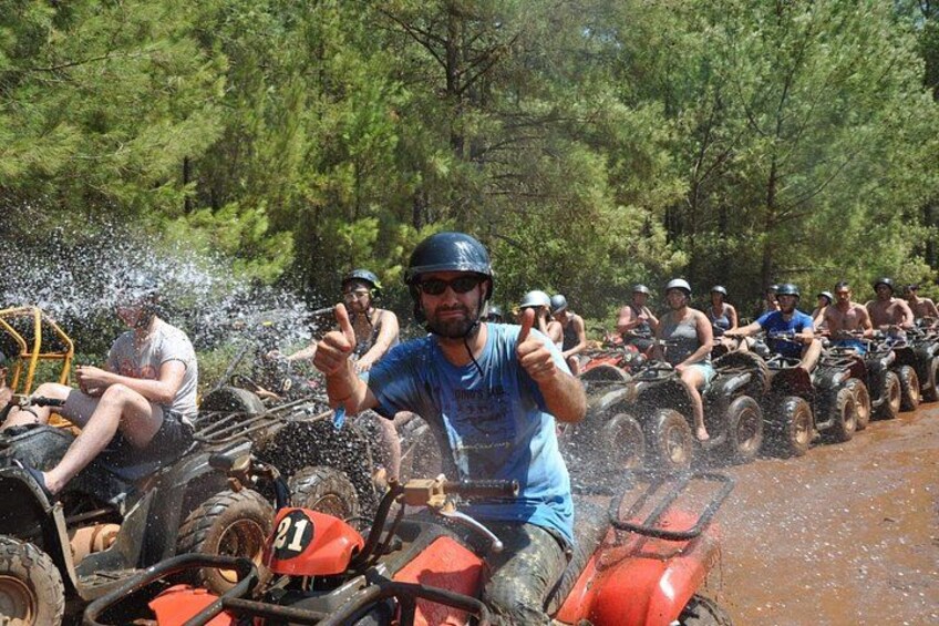 People riding atv's through a muddy path with water splashing. 4