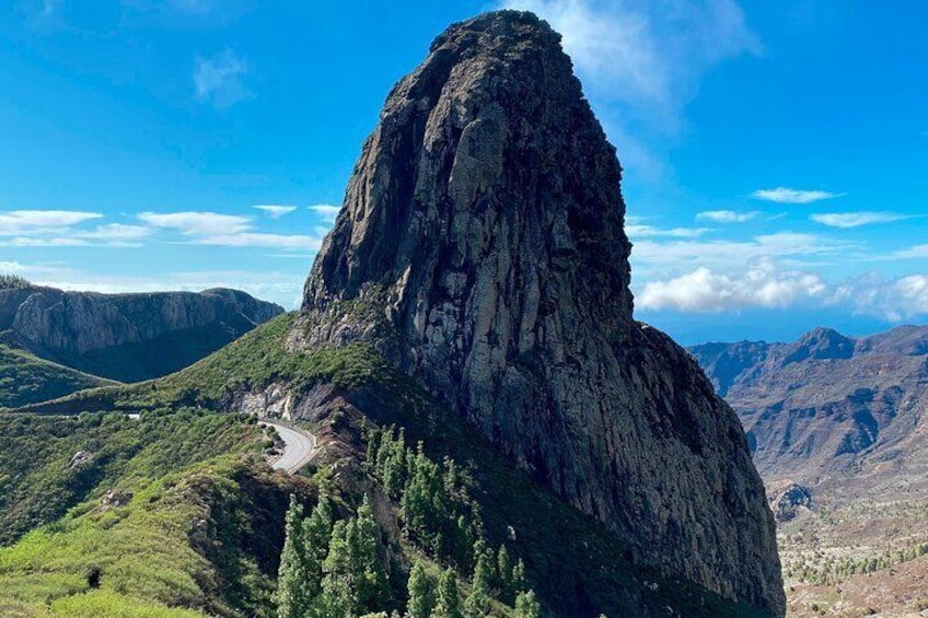A rugged mountain peak with a winding road leading up to it. 1
