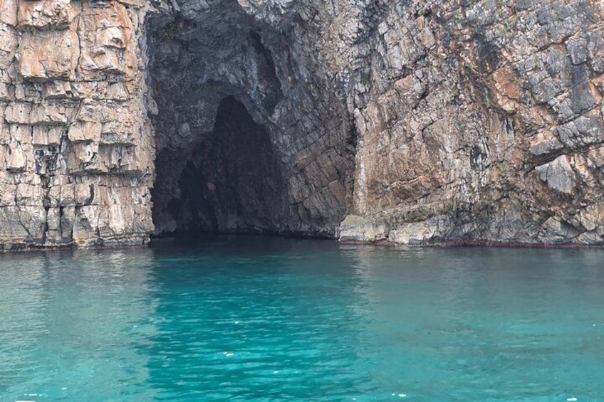 L'entrée d'une grotte rocheuse, avec une eau turquoise et limpide. 3