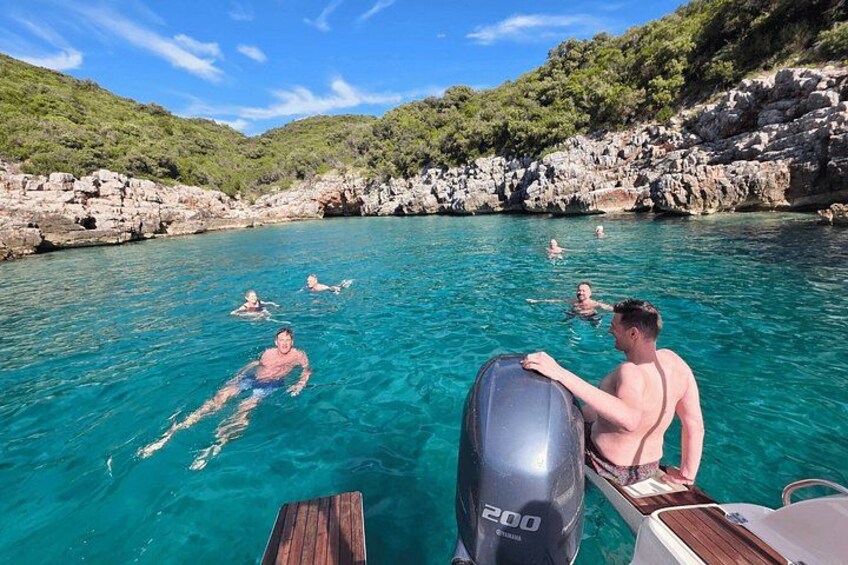 Un bateau à moteur, portant le numéro « 200 », navigue sur une mer bleue et limpide, entouré de falaises rocheuses et de verdure. 4