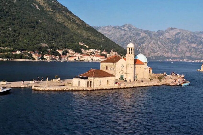 A coastal town with a prominent church on a small island, surrounded by mountains and a clear blue sea. 2