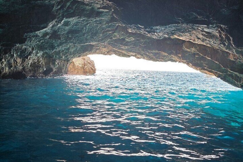 A natural rock formation with a cave entrance and clear blue water. 3