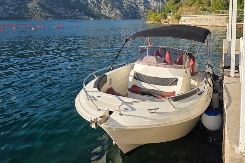 A small boat docked at a pier with a rocky shoreline in the background. 3