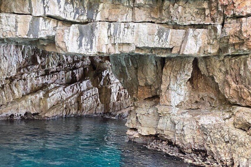 A rocky cliff with a clear blue pool at the base. 2