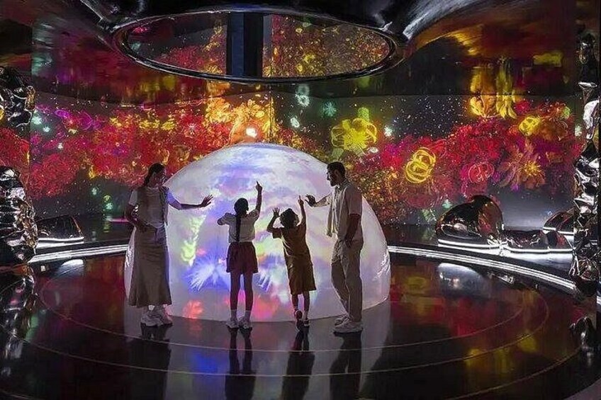 A group of people in a futuristic setting with a large, illuminated globe and vibrant, colorful projections on the walls. 5