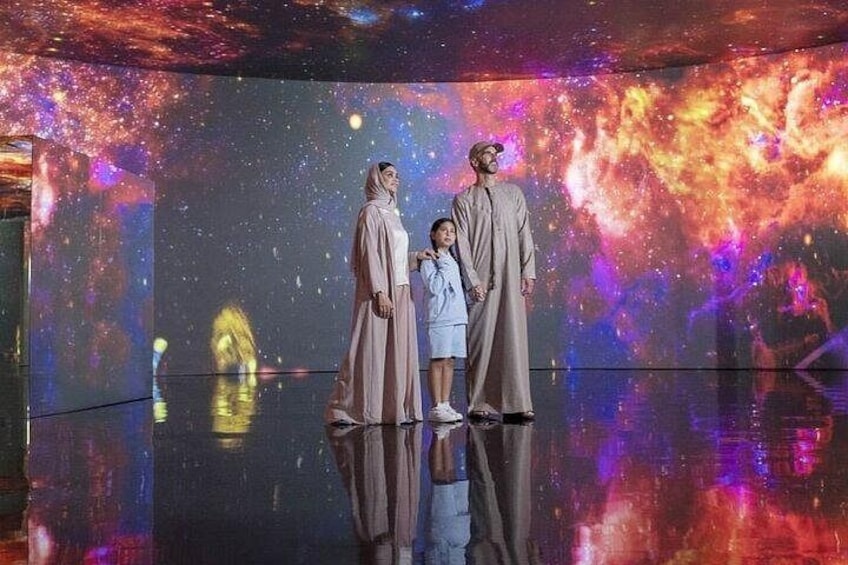 A person in traditional attire standing in front of a cosmic-themed backdrop. 3