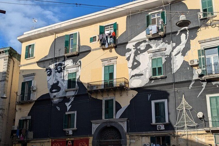 Un edificio con un gran mural de un rostro, balcones y una decoración de telaraña. 4