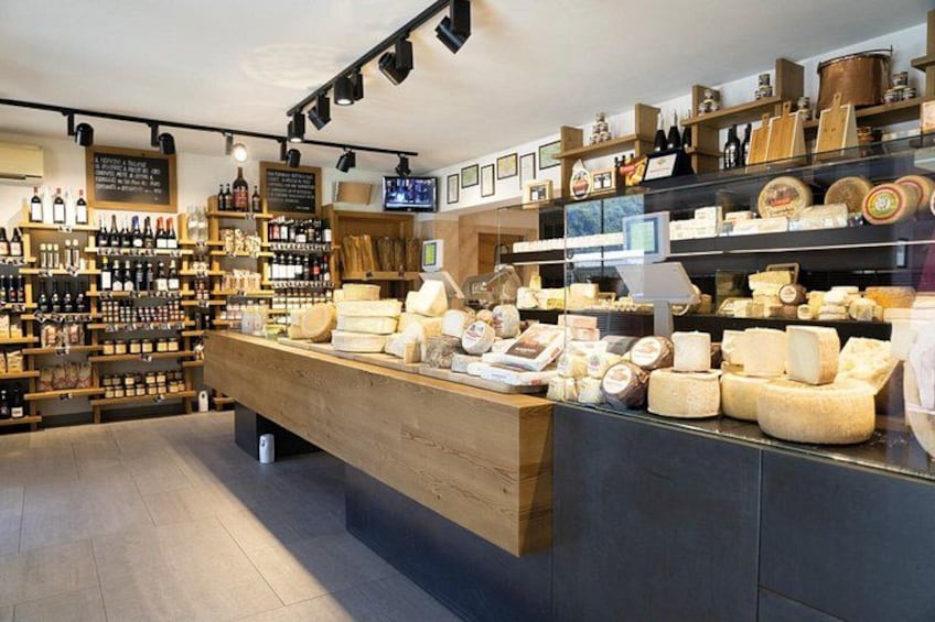 A cheese shop with wooden shelves and a display counter. 1