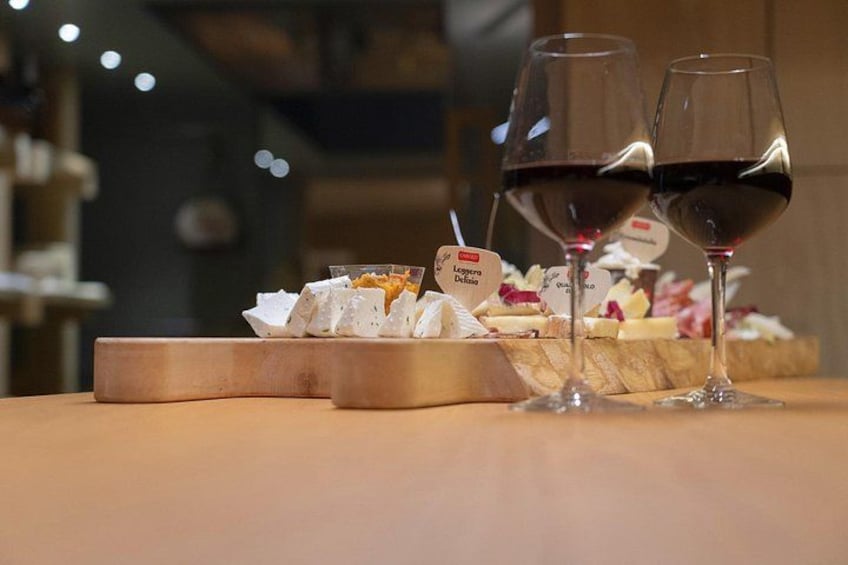 A wooden table with two glasses of red wine and a small dish of cheese. 3