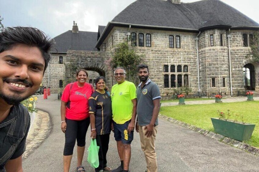 A group of people standing in front of a large stone building with a garden. 3