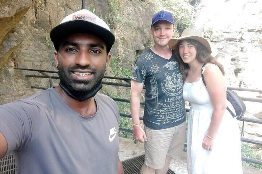 A person in a grey t-shirt and cap, a man in a blue t-shirt and cap, and a woman in a white dress standing near a rocky cliff. 5