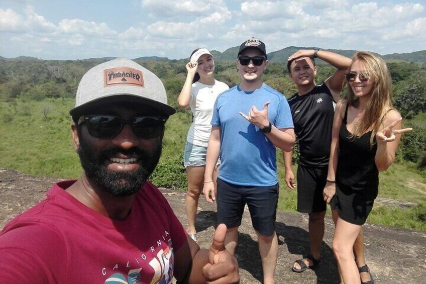 A group of people standing on a rocky outcrop with a mountainous landscape in the background. 1