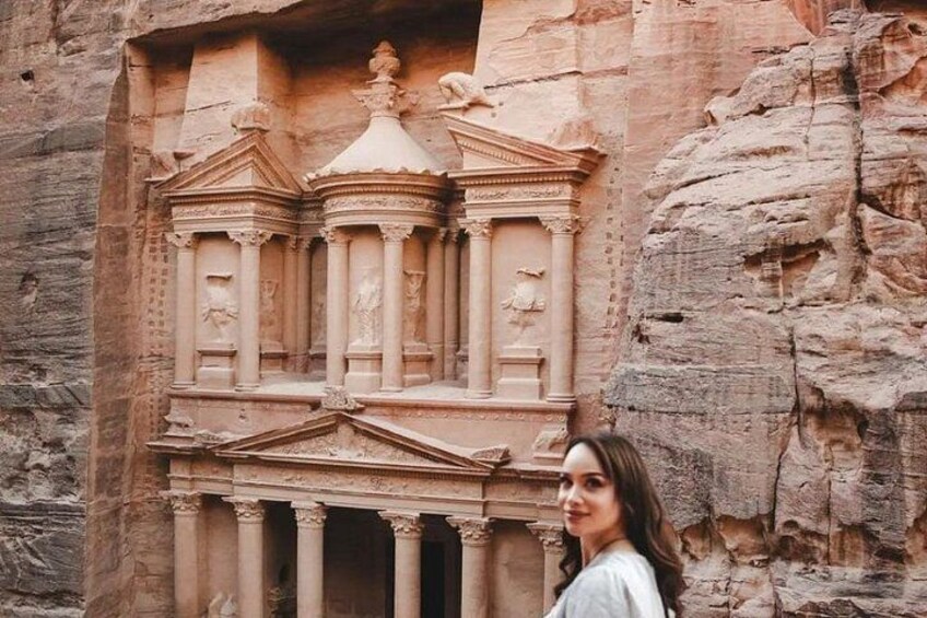 A carved facade with columns and a central statue, set against a rocky cliff. 1