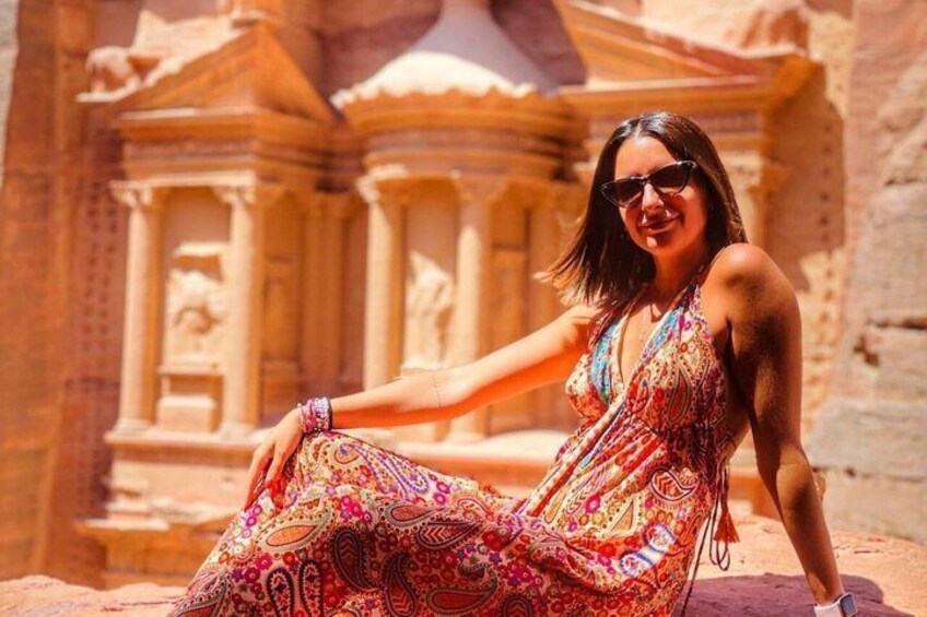 A person sitting in front of an ancient stone structure with columns. 4