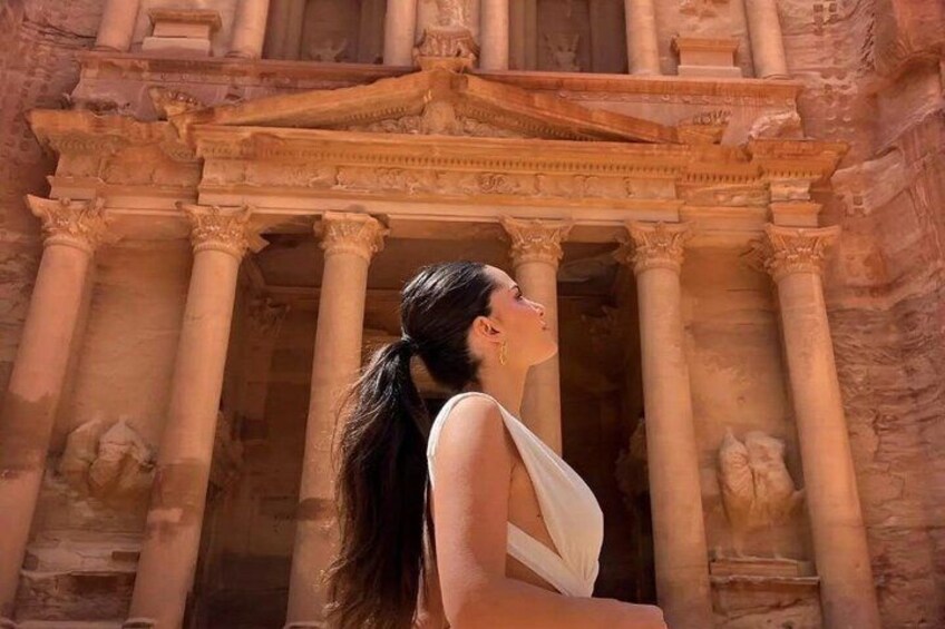 A person standing in front of a large, ancient stone structure with columns and intricate carvings. 5