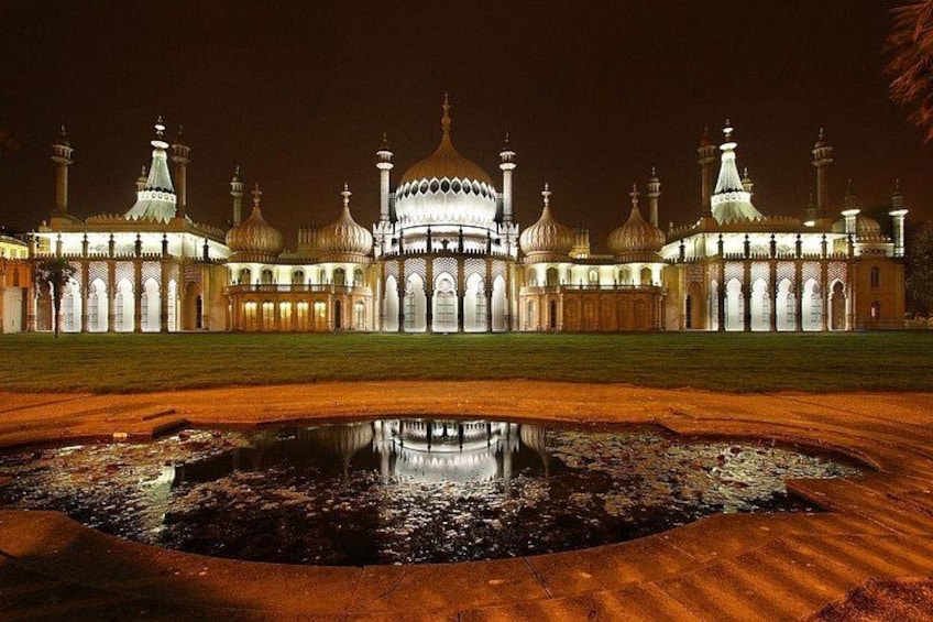 A large, illuminated mosque with multiple domes and minarets, a central dome, and a reflection in a water feature at its base. 5