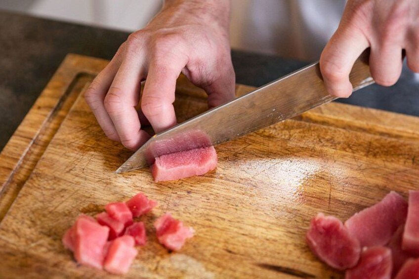 A person chopping watermelon on a wooden cutting board. 2