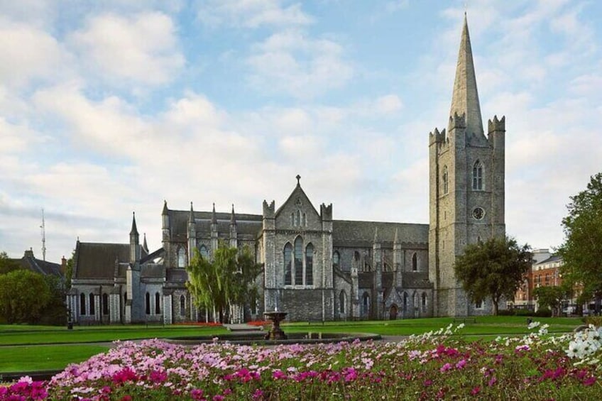 A historic church with a tall spire and a well-maintained garden in front. 3