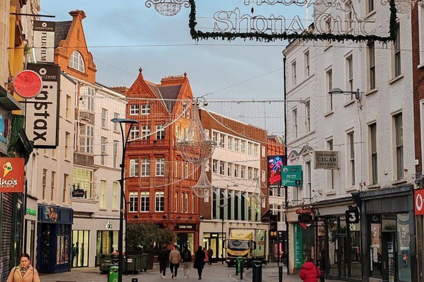 A street with historic buildings, a tram, and pedestrians. 4