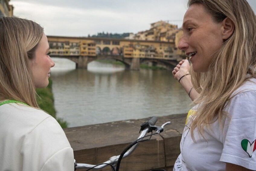 Two people standing by a river with a bridge in the background. 3