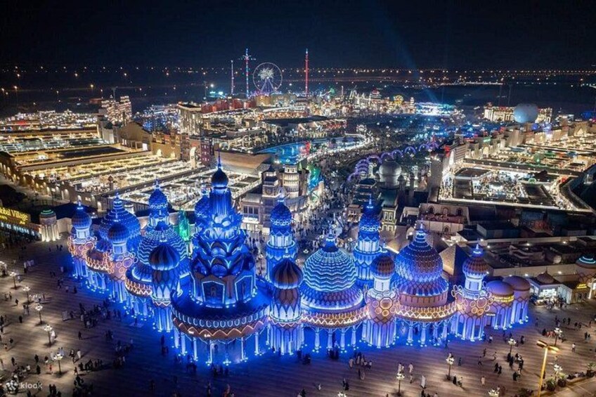 A large illuminated structure with multiple domes, surrounded by a crowd of people. 4