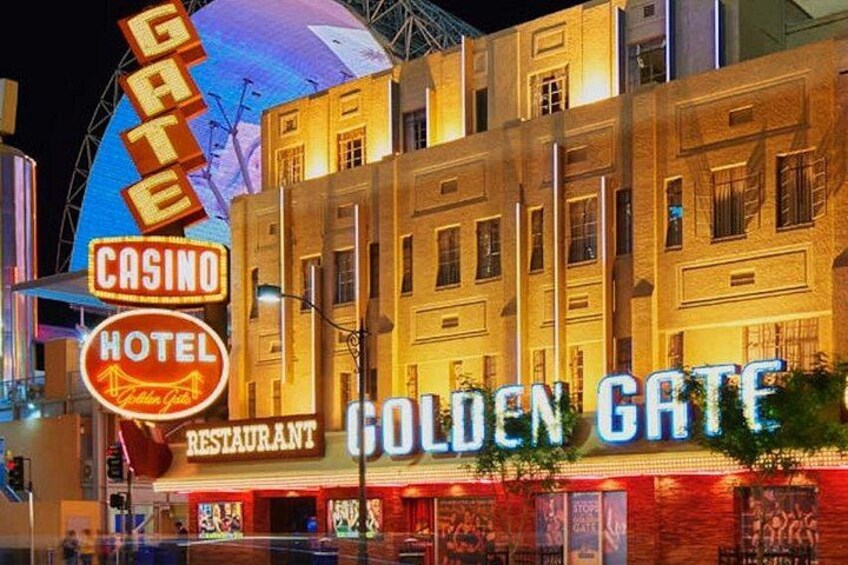 El Hotel Casino Golden Gate con letreros iluminados y una noria al fondo. 5