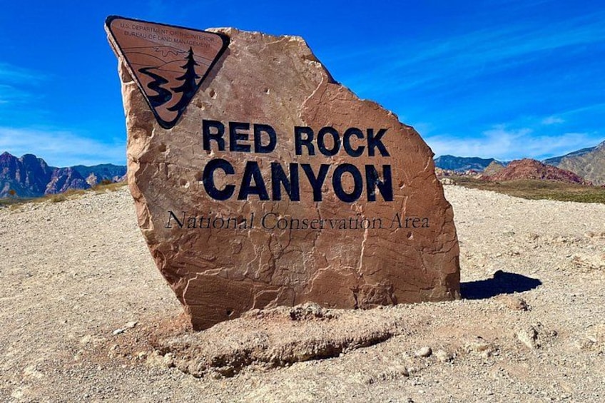 Una gran roca con el texto 'RED ROCK CANYON Área de Conservación Nacional' y un logotipo. 3