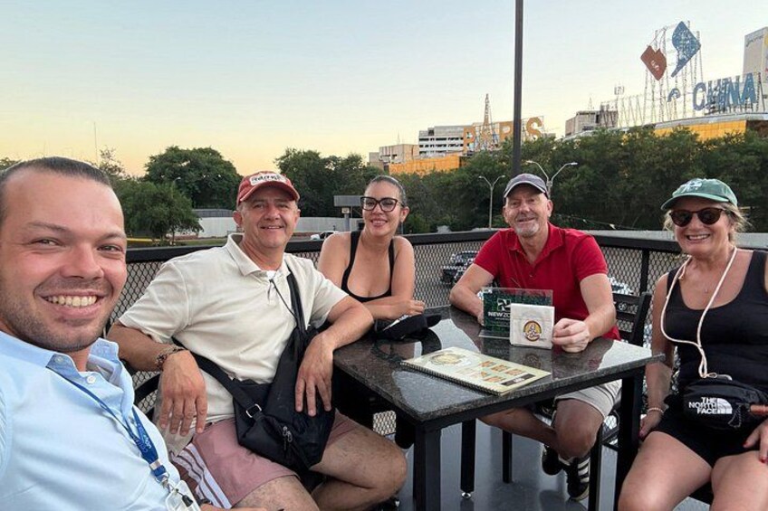 A group of people sitting at an outdoor table with a cityscape in the background. 3