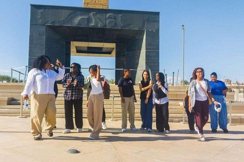 A group of people standing in front of a modern building with inscriptions. 5